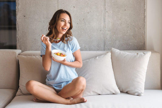Woman sitting on the couch holding a bowl with food 