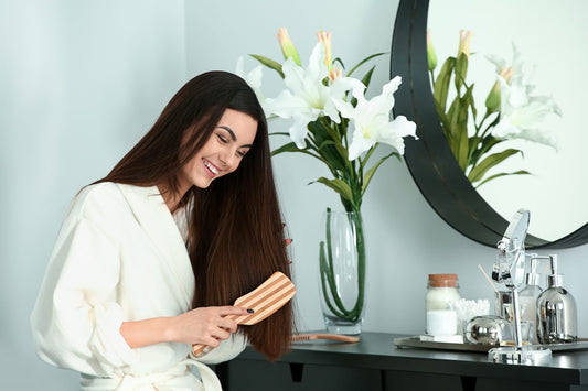 Woman in a bathrobe brushing her hair and smiling