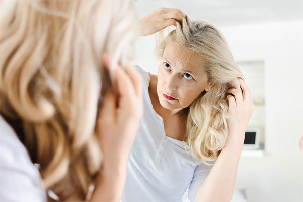 woman inspecting her hair in front of the mirror