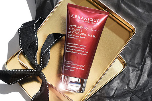 Keranique micro-exfoliating hair mask placed on a golden tin box with a black ribbon next to it