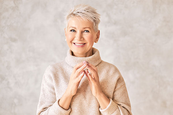 woman with a pixie cut and beige sweater smiling
