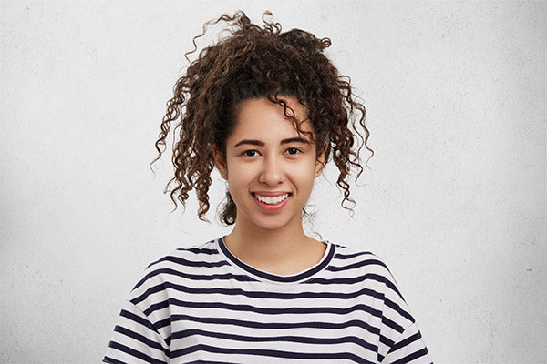 A woman with black curly hair smiling