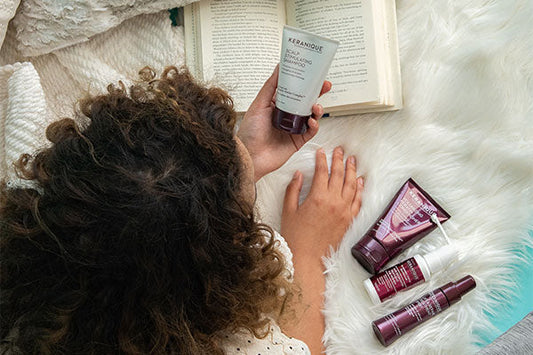 woman laying in bed looking at keranique hair products