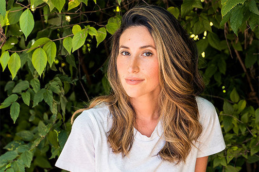 A woman wearing white shirt with trees in the background