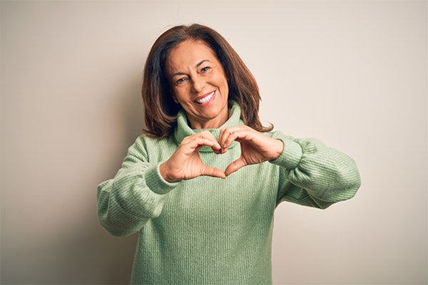 a woman wearing green sweater making a heart with her hands