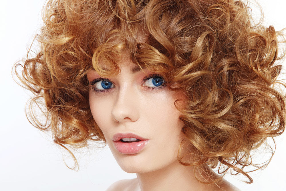 Woman with blue eyes and brownish red curly hair 