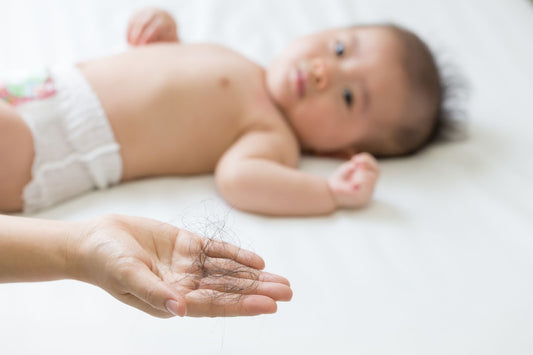 Hand with hair strands and a baby  in the background