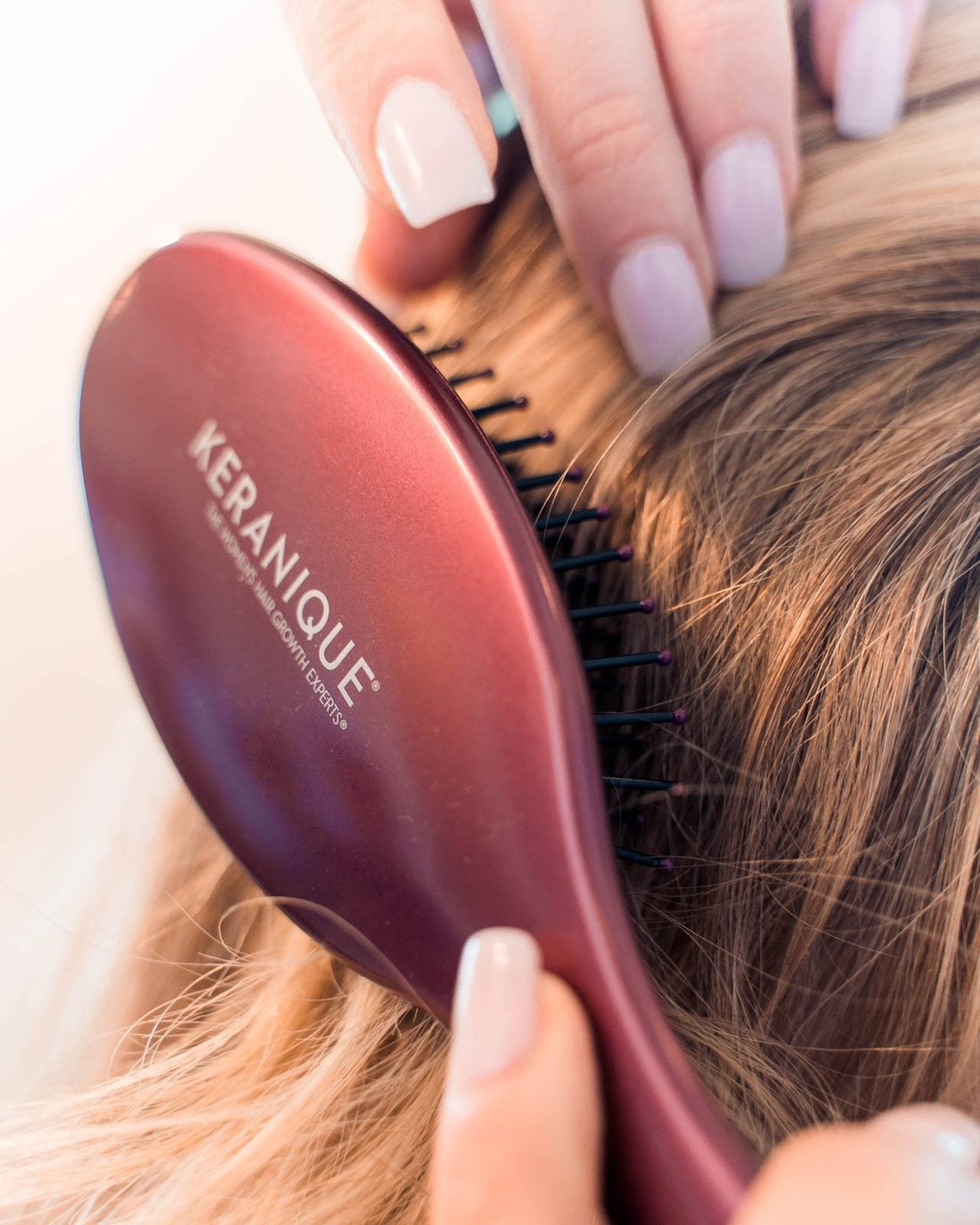 Someone brushing their hair with a keranique hair brush